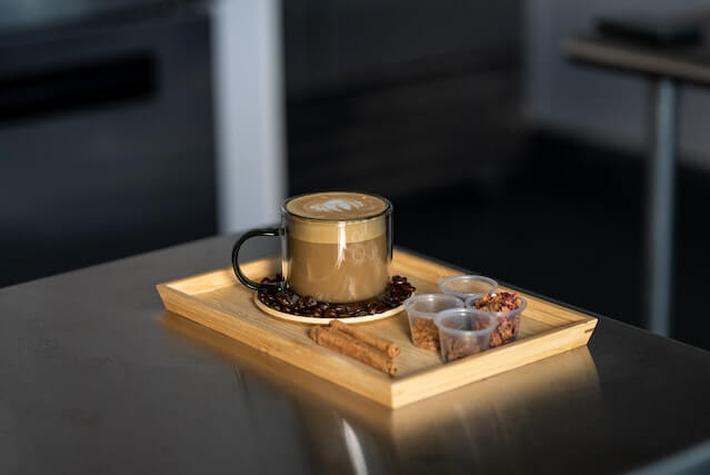 A cup of coffee and vanilla sticks on a tray