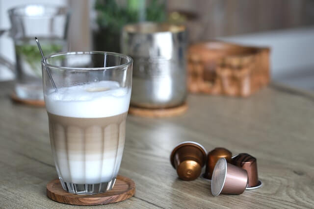 latte macchiato coffee in a glass and coffee capsules