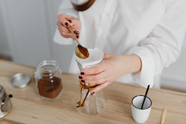 A woman holding a spoon scooping coffee powder